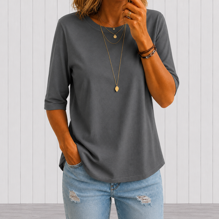 Woman wearing the green crew-neck tee with longer half sleeves and a curved hem.