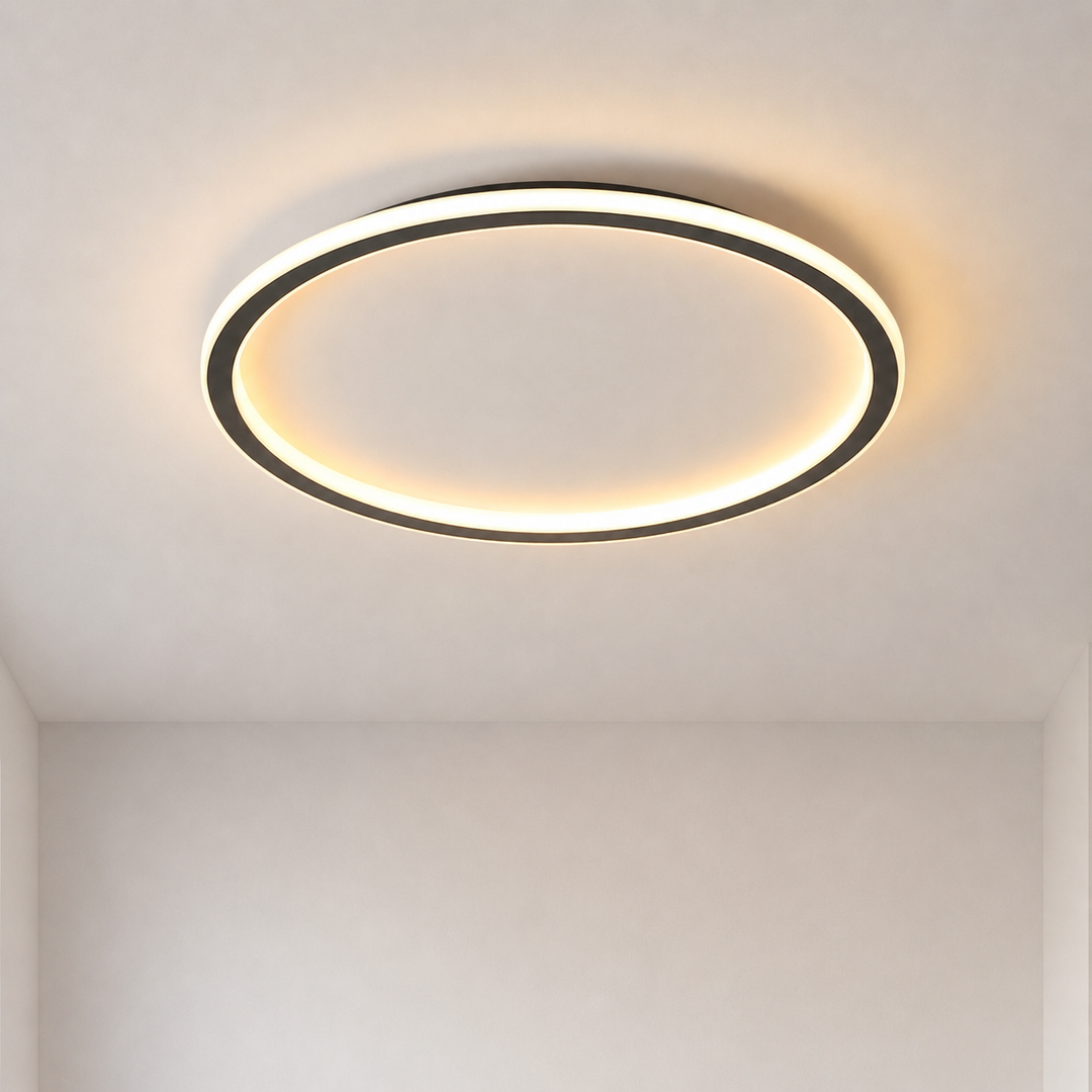 Lit round ceiling light with a black outer rim and glowing ring, seen straight on against a plain light ceiling. 1