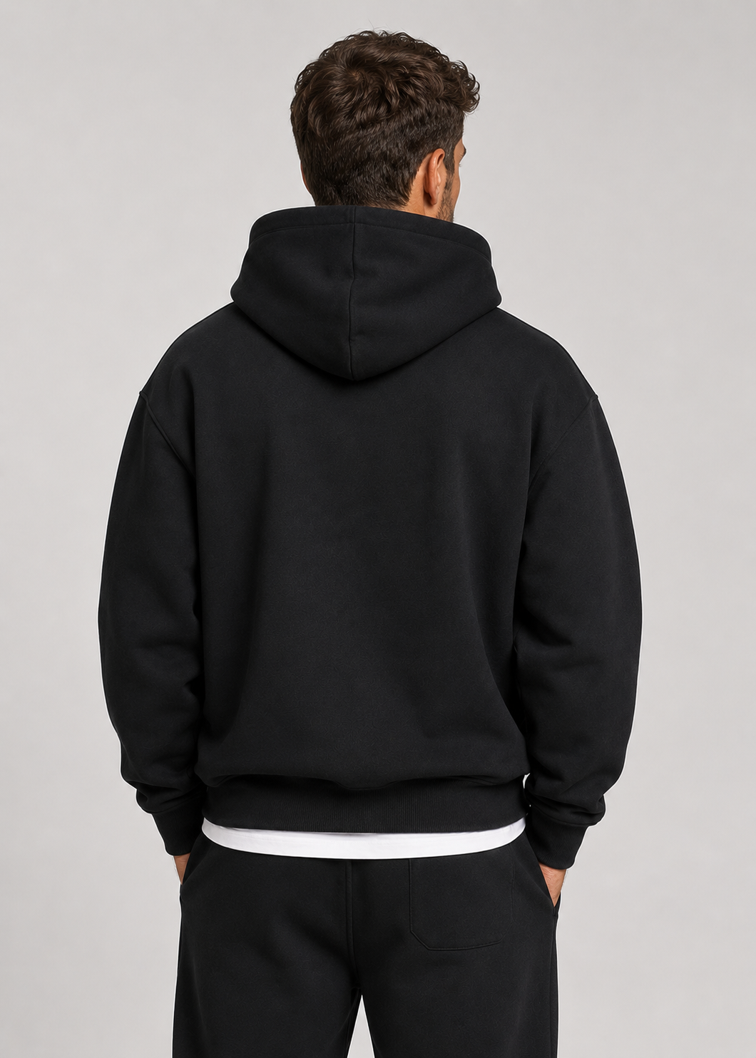 Men's black hoodie and jogger set, back view showing the patch pocket on the pants and ribbed hem.