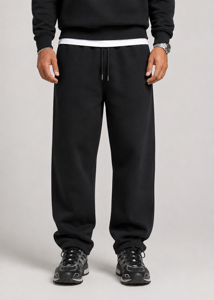 Men's black joggers detail, front view showing the drawstring waistband and straight legs.