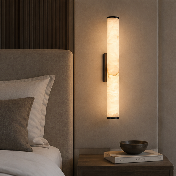 Marble sconce with dark caps used as a bedside light above a wooden nightstand holding a bowl and books next to an upholstered headboard.