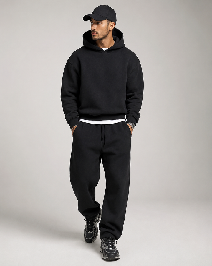 Men's black hoodie and jogger set, three-quarter view on a studio background.