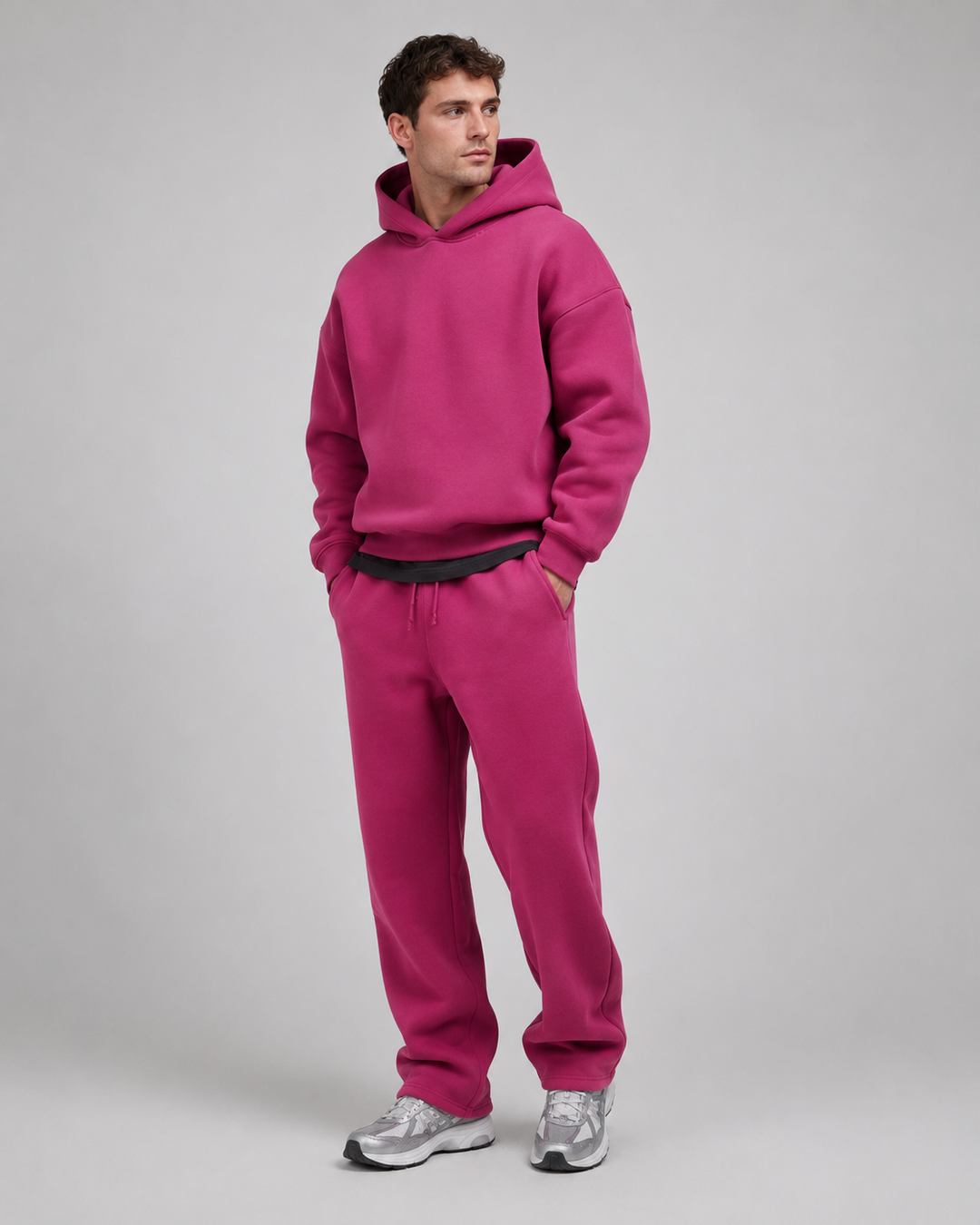 Men's magenta pink hoodie and joggers, studio view with a dark tee underneath.