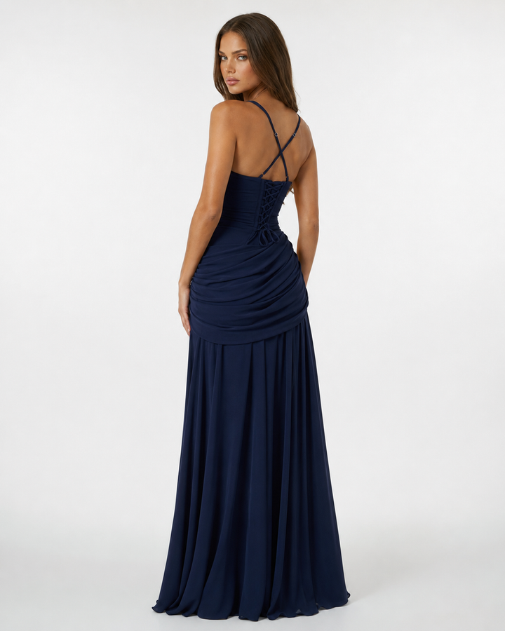 Back view of a navy blue maxi dress with crossed straps, lace-up corset back and gathered hip drape