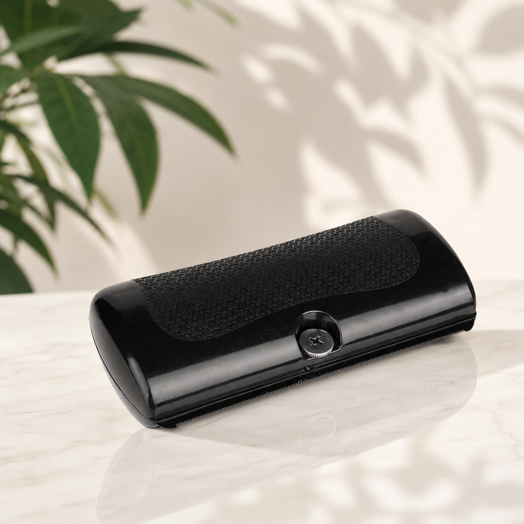 GlowBrush black grooming comb resting on a white marble surface beside a green plant.