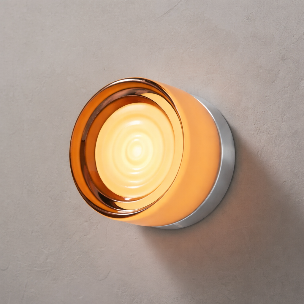 Wall lamp with amber-orange glass glow, ripple center and silver base, mounted on a textured gray wall. 33