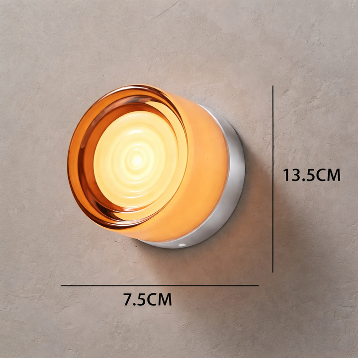Amber glass wall lamp with a glowing center on a textured gray wall, annotated with 13.5 cm and 7.5 cm dimensions.