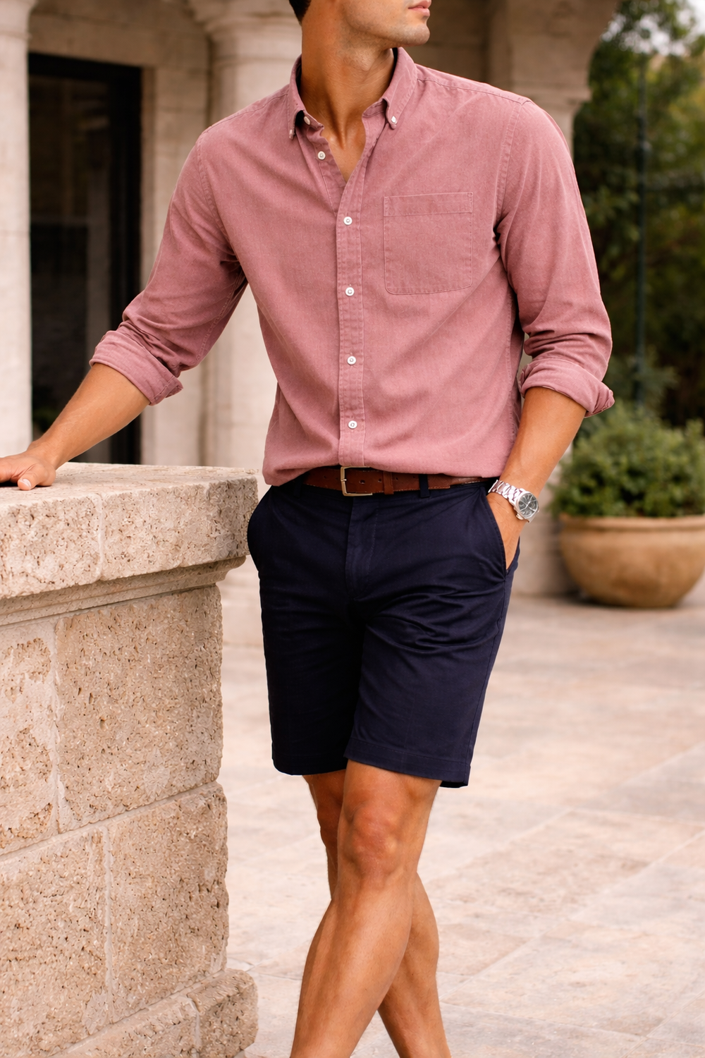 Men's cotton button-down shirt in pink, worn with rolled sleeves.
