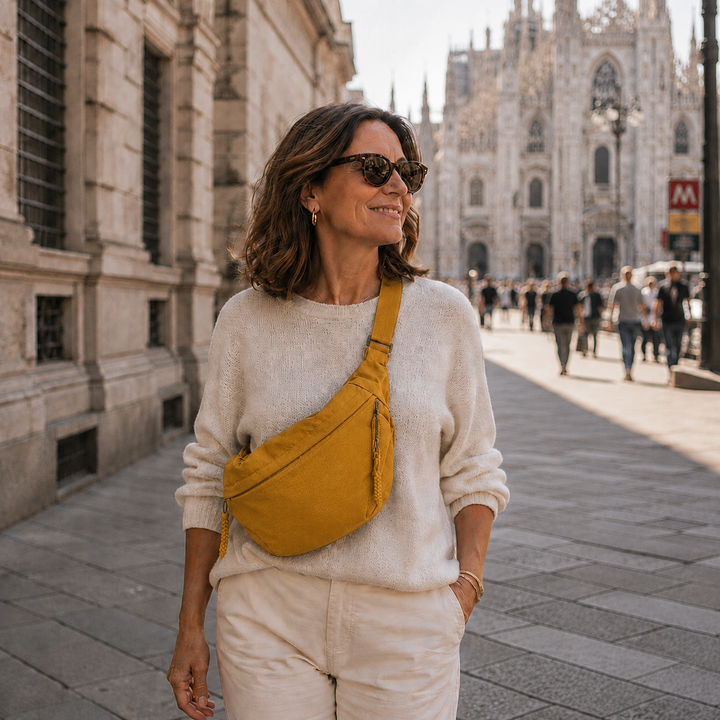 Smiling woman in sunglasses and a cream sweater wears the ochre bag across her chest outdoors 4