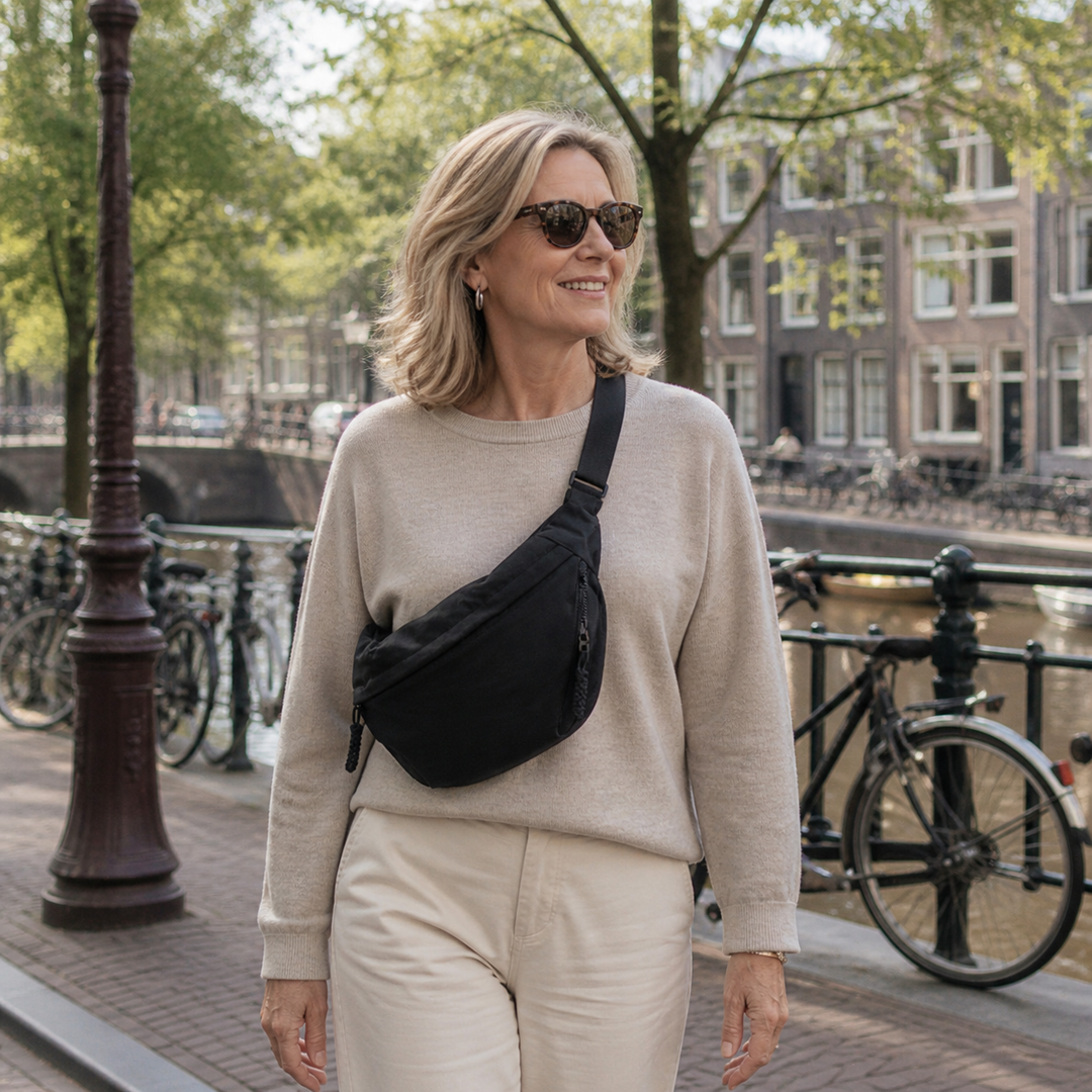 Black bag worn crossbody on a woman crossing a canal bridge.