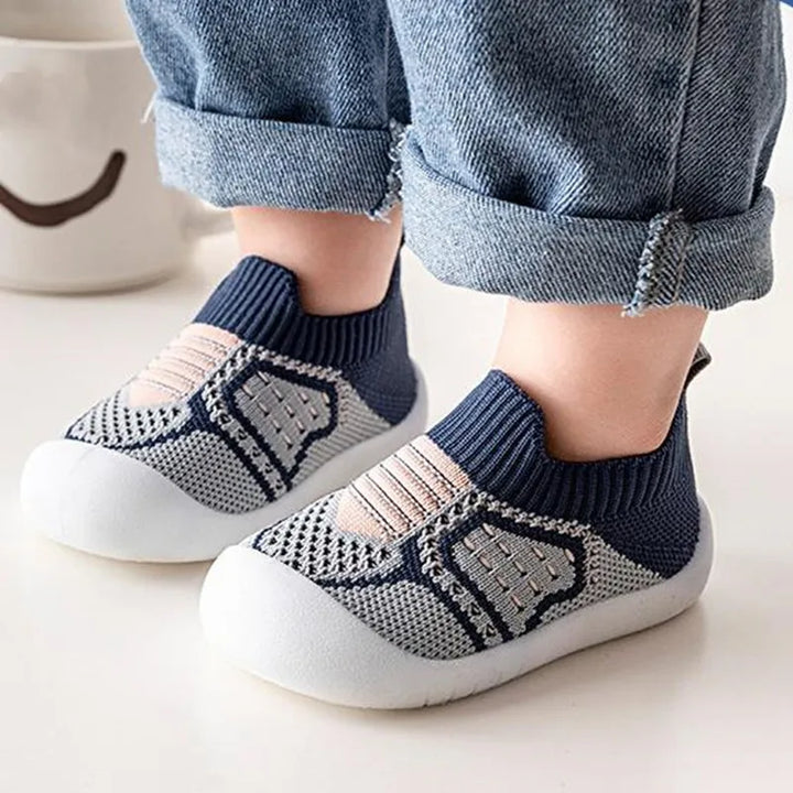 Navy and gray knit slip-on baby shoes with white soles, detail.