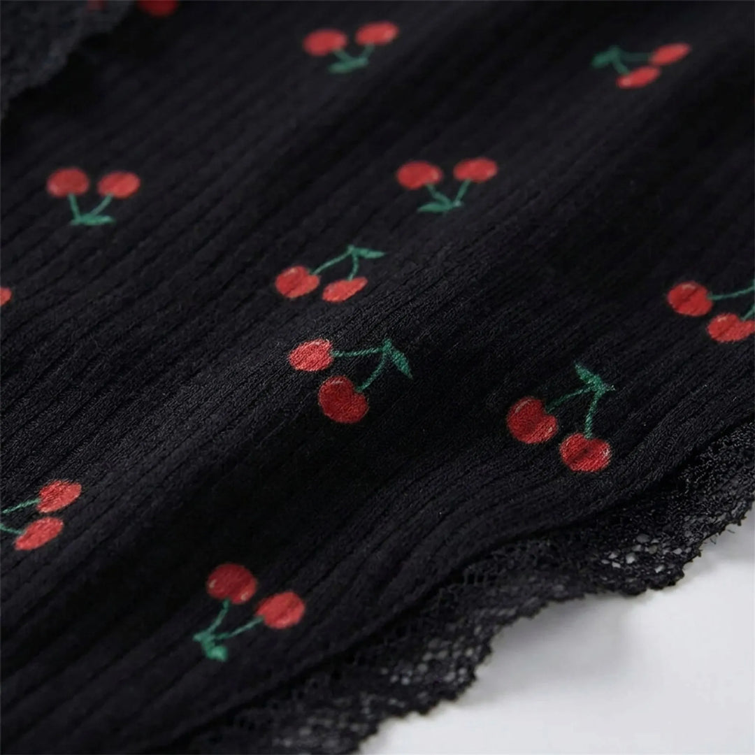 Close-up of the black ribbed knit fabric with a red cherry print and scalloped black lace edging. 5