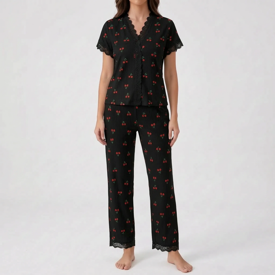 Front view of the black cherry-print pajama set on a model against a plain backdrop, with lace V-neck, sleeves and pant hems. 7