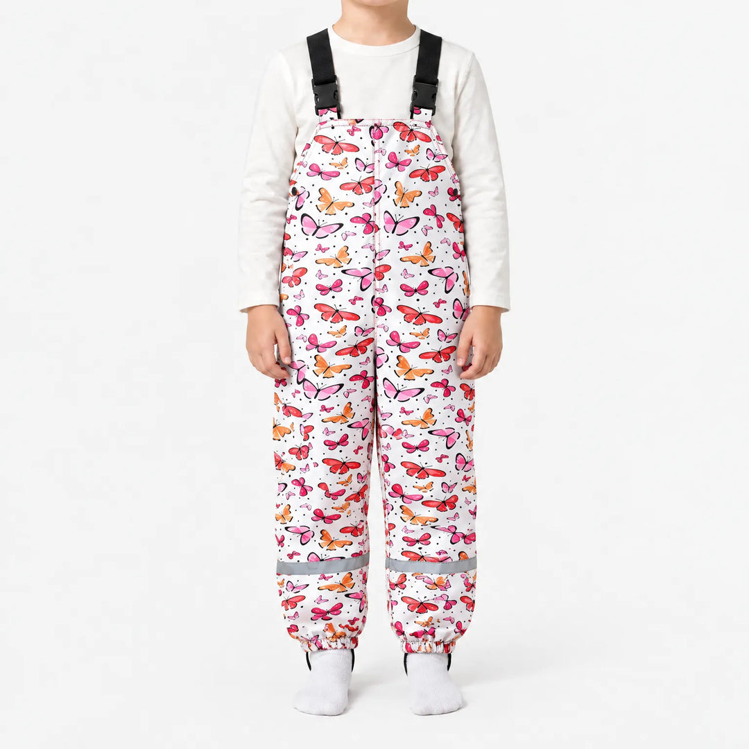 Child wearing white dungarees covered in pink, red and orange butterflies, with black buckled straps, side snaps and reflective ankle bands. 14