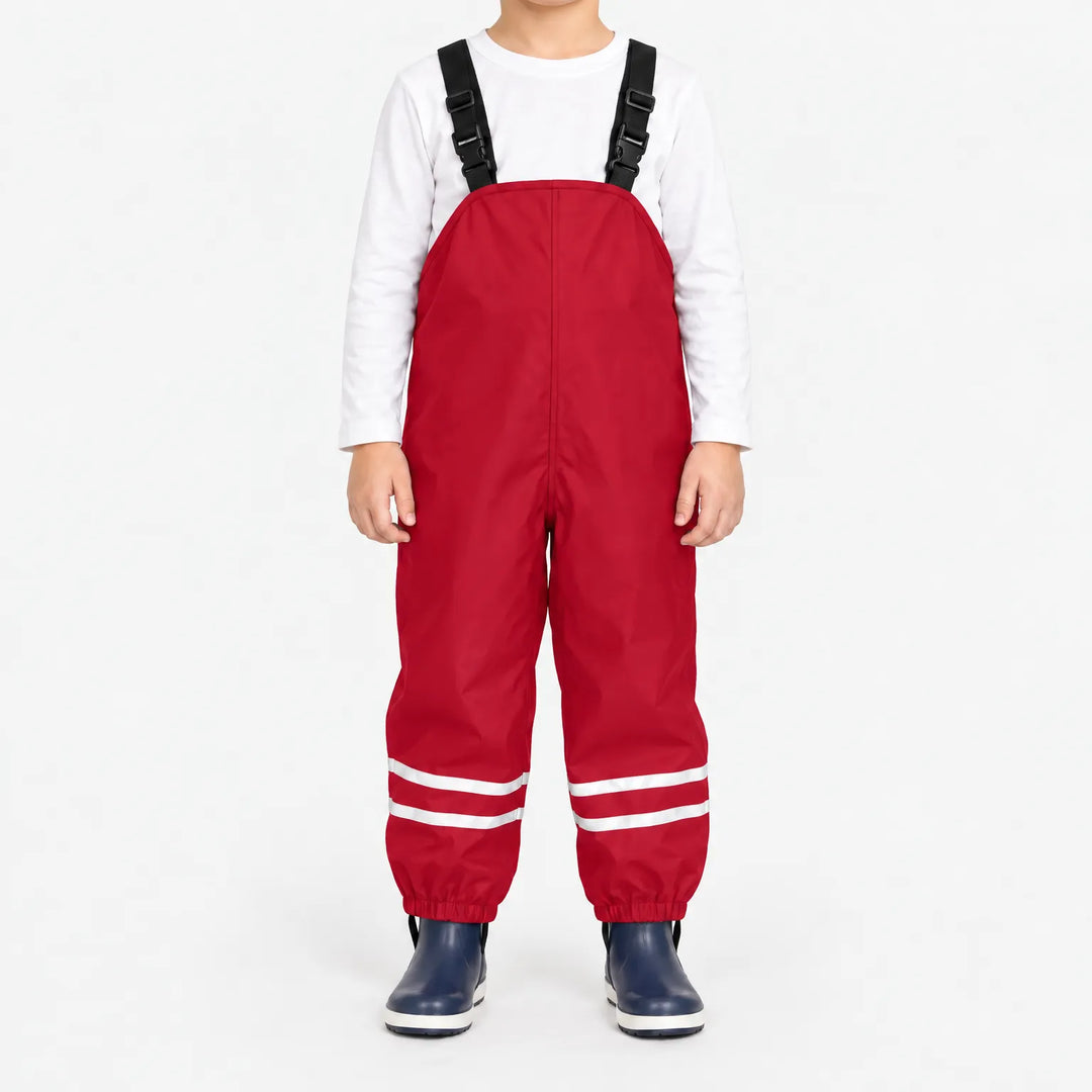Front view of child wearing red waterproof overalls with black buckled straps and reflective stripes at the ankles, paired with navy boots. 11