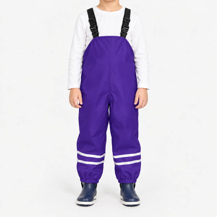 Front view of child wearing purple waterproof overalls with black buckled straps, reflective ankle stripes and elastic cuffs, with navy rain boots. 12