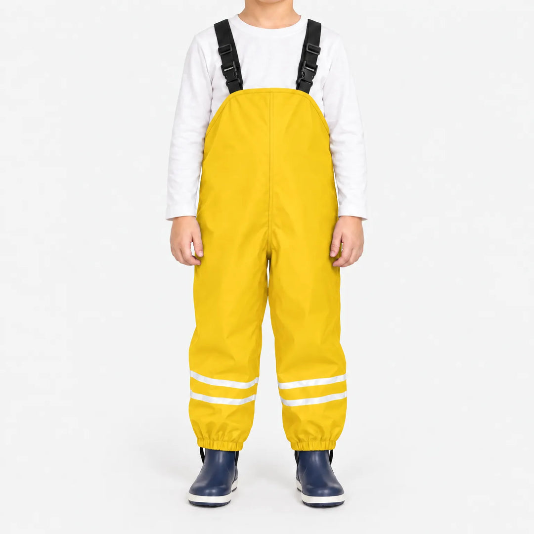 Front view of child wearing yellow waterproof overalls with black buckled straps, reflective ankle stripes and elastic cuffs, with navy rain boots. 14