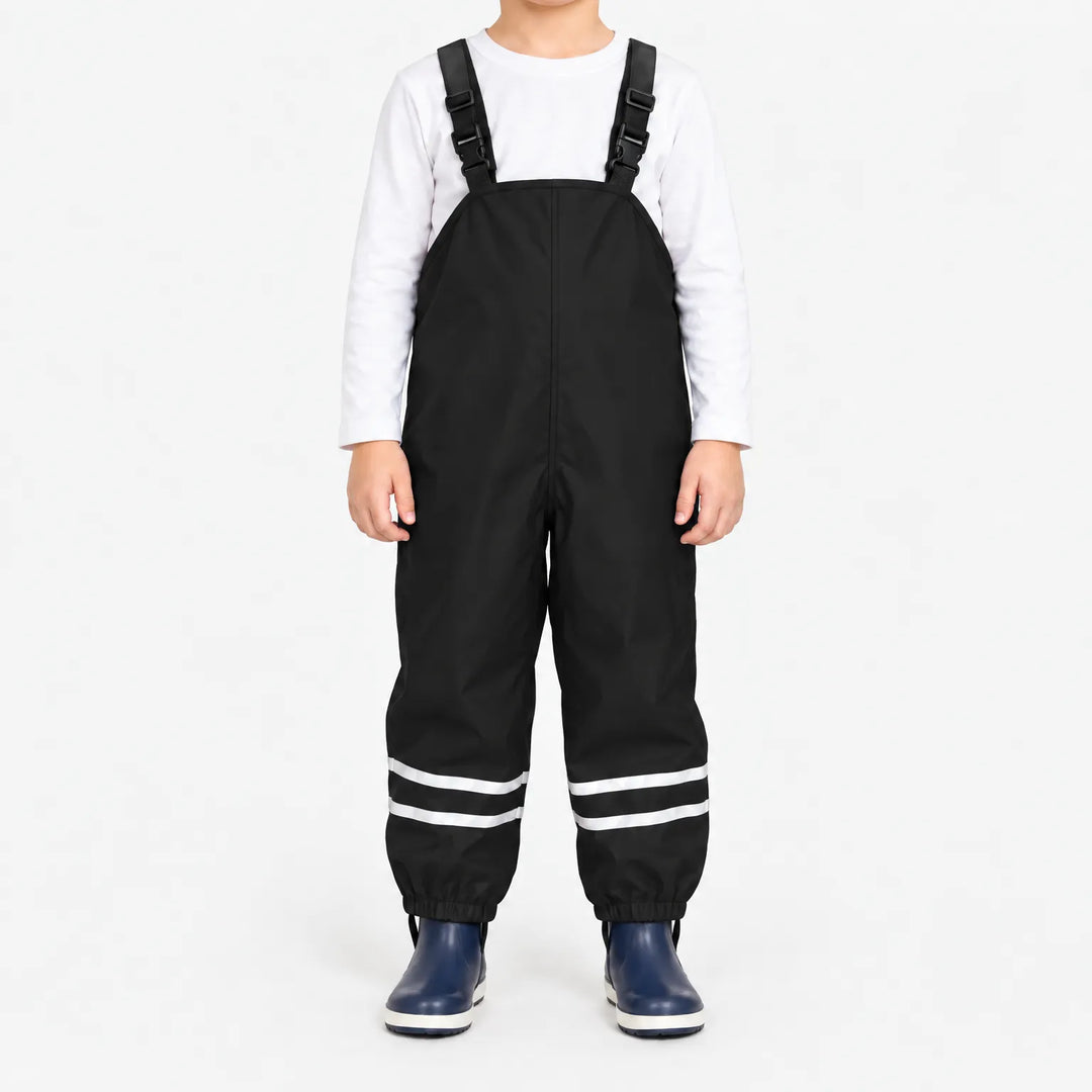 Front view of black waterproof overalls with buckled shoulder straps and reflective stripes at the ankles, worn with a white shirt and navy boots. 7