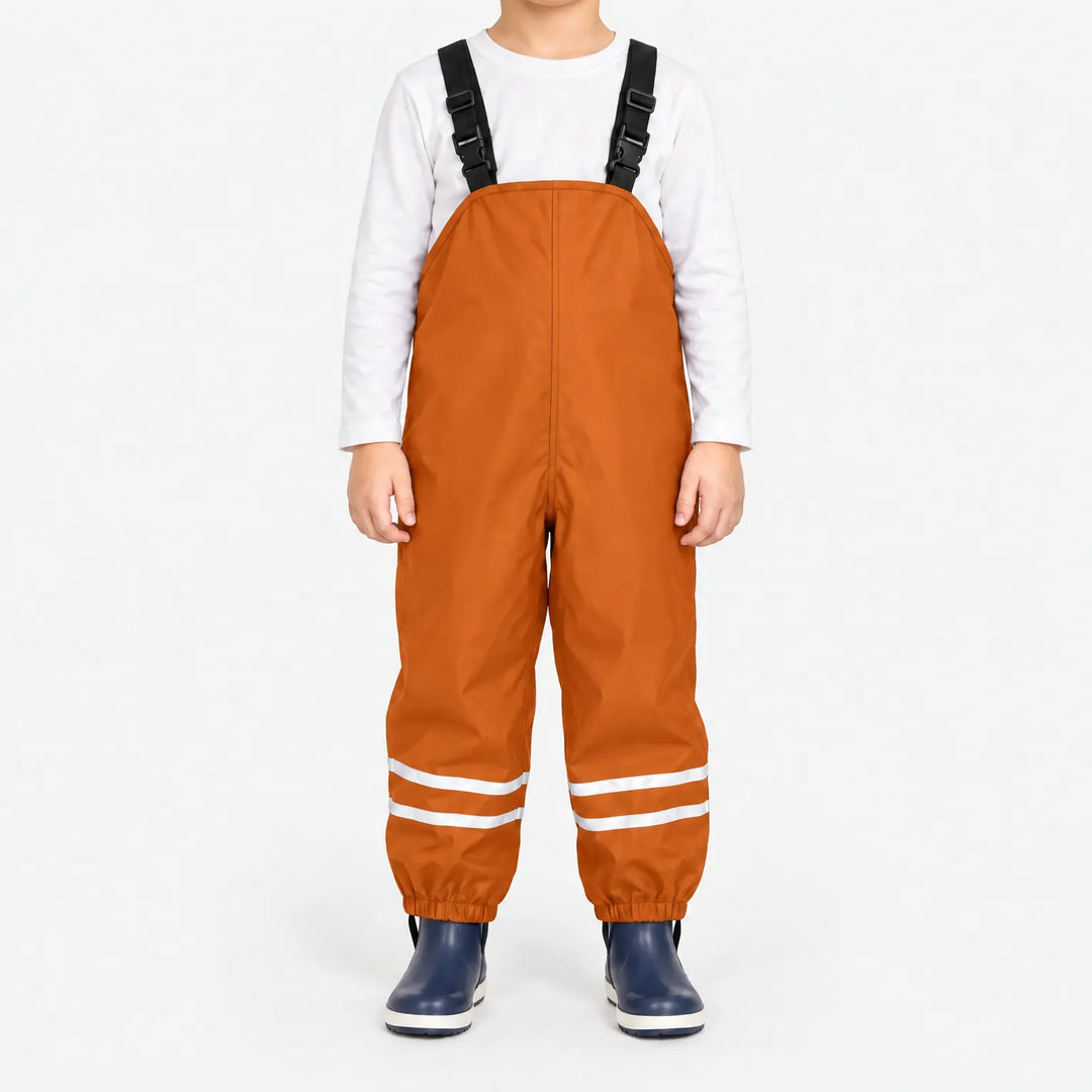 Front view of child in orange waterproof overalls with black buckled straps, reflective ankle stripes and elastic cuffs over navy rain boots. 8