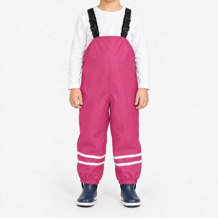 Front view of child wearing bright pink waterproof overalls with black buckled straps and reflective ankle stripes, with navy rain boots. 9