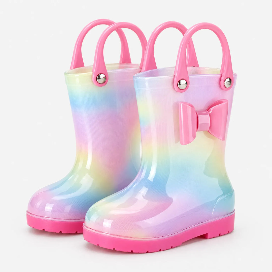Pair of pastel rainbow rain boots with two pink carry handles each and a pink bow on one boot. 2