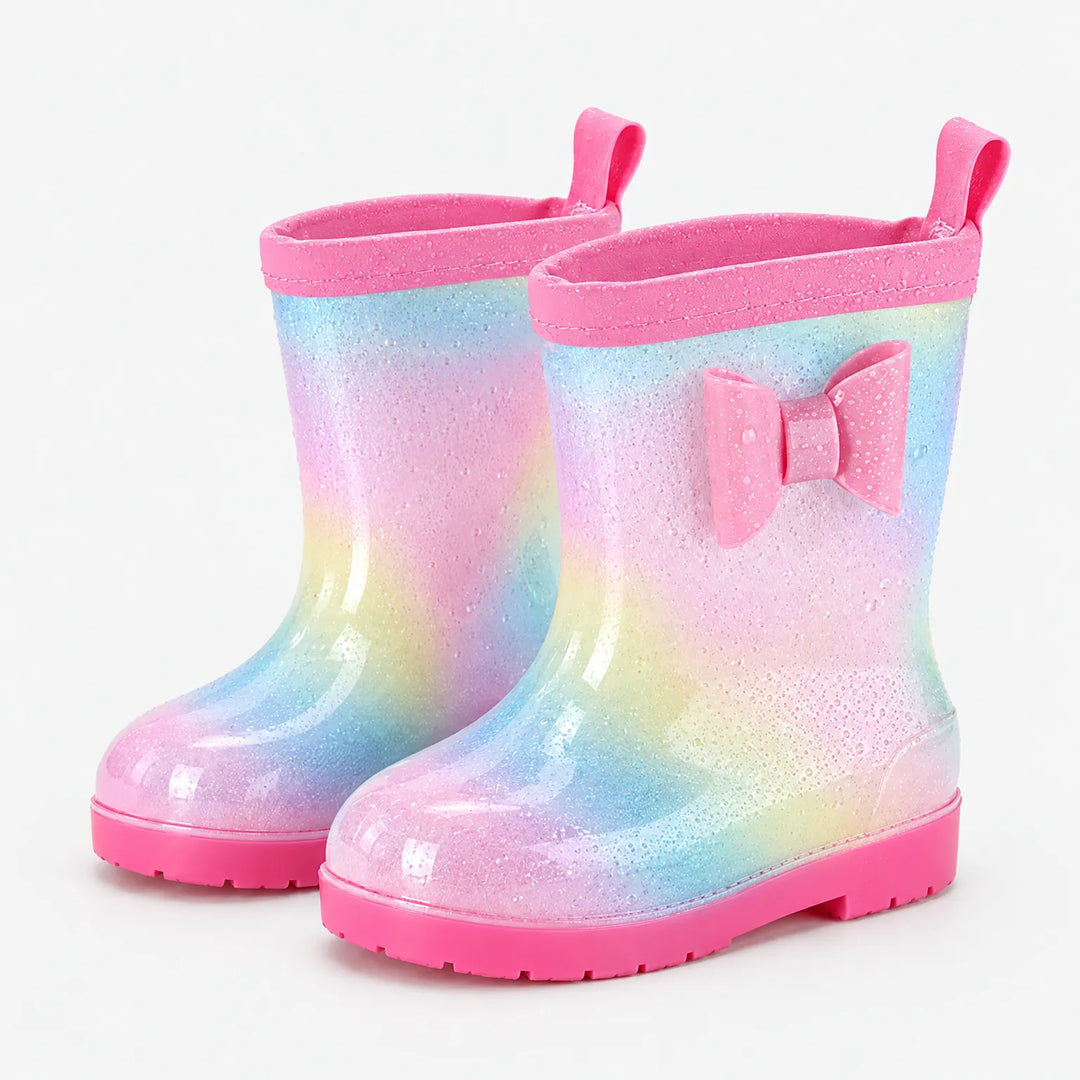 Pair of glittery pastel rainbow rain boots with pink bow, pink pull tab, pink trim and water droplets on the surface. 7