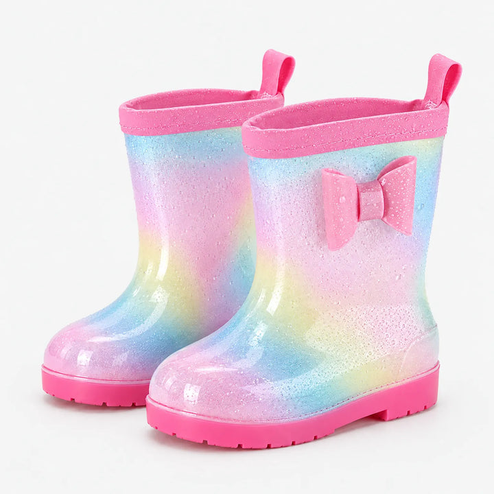 Pair of glittery pastel rainbow rain boots with pink bow, pink pull tab, pink trim and water droplets on the surface. 7