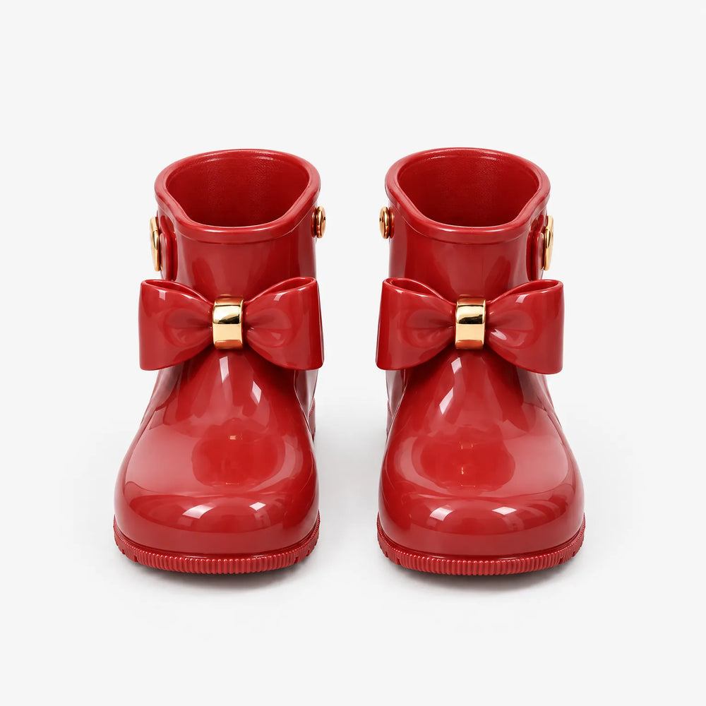Pair of glossy red rain boots seen from the front on a white background, each with a bow and gold ring. 2