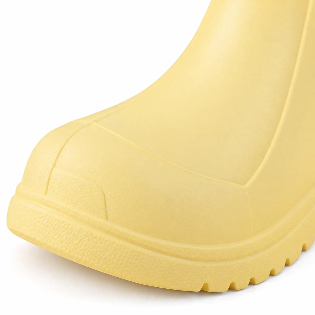Close-up of a yellow rain boot toe showing the molded toe cap, seam lines and ridged tread sole. 6