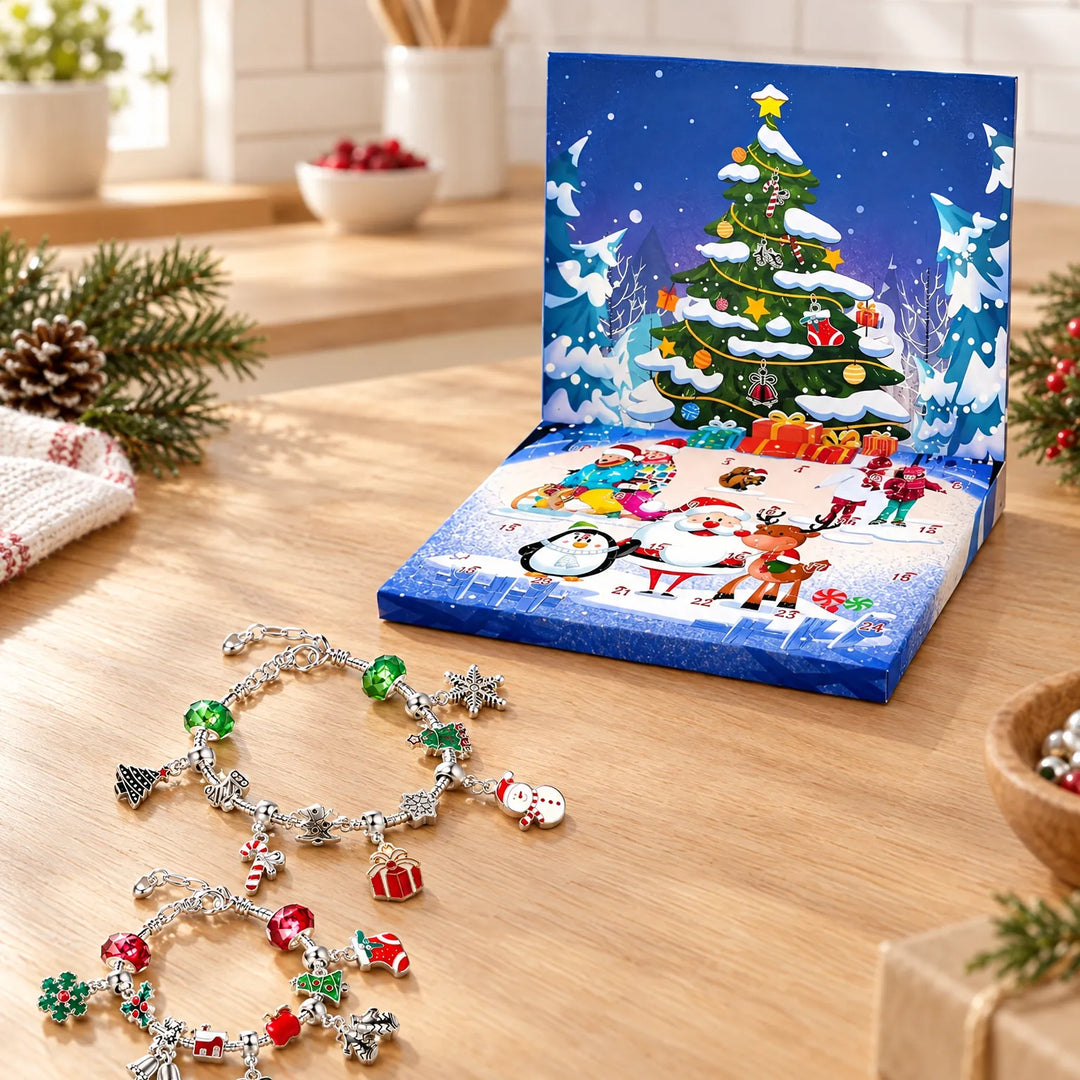 Two silver charm bracelets with festive charms lie on a wooden table beside the open blue winter-scene advent box. 1