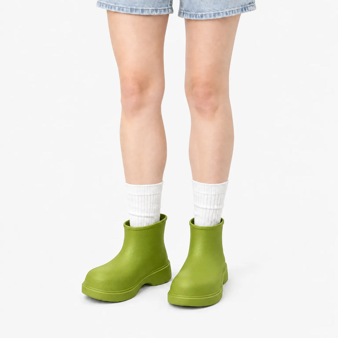 Olive green ankle boots worn with white ribbed socks and denim shorts, front view on a white background. 10