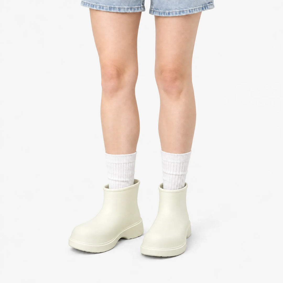 Cream ankle boots worn with white ribbed socks and denim shorts, front view on a white background. 9