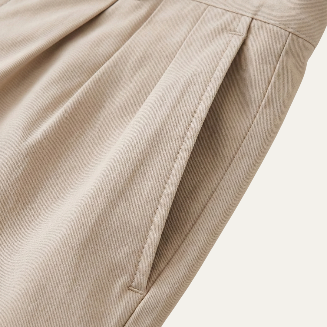Close-up of a beige side pocket opening with topstitching and a subtle twill weave fabric texture.