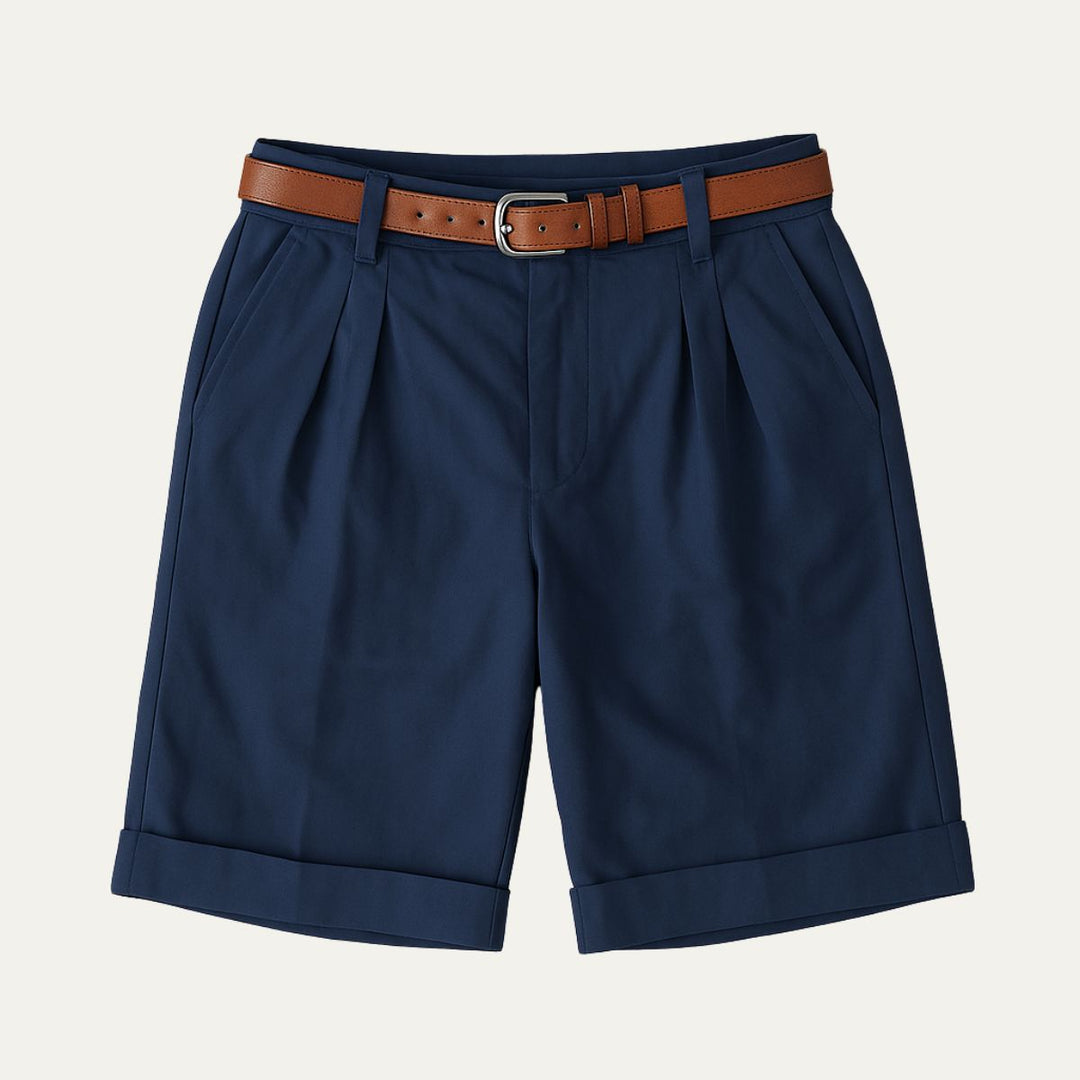 Flat lay of navy double-pleated shorts with turn-up hems and a tan leather belt with silver buckle.