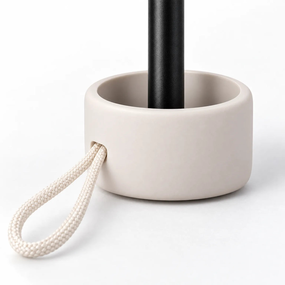 Close-up of the umbrella's cream handle base with a braided cord loop and the black shaft rising from it. 5