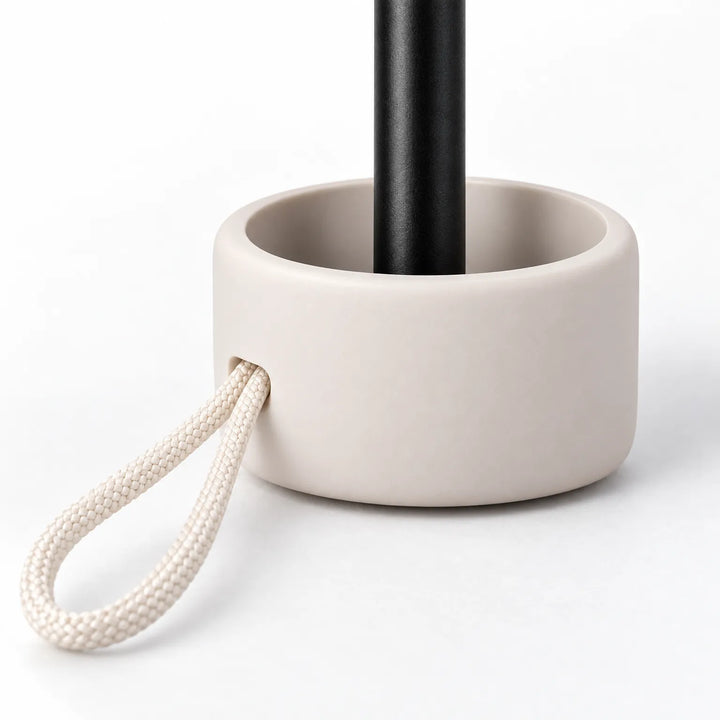 Close-up of the umbrella's cream handle base with a braided cord loop and the black shaft rising from it. 5