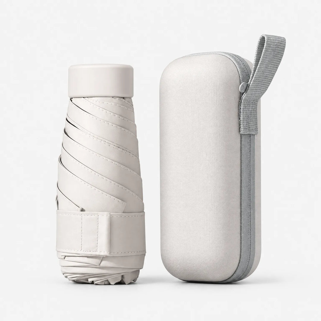 Folded cream umbrella with strap and cap next to its matching cream hard case with a gray zipper and carrying loop. 6