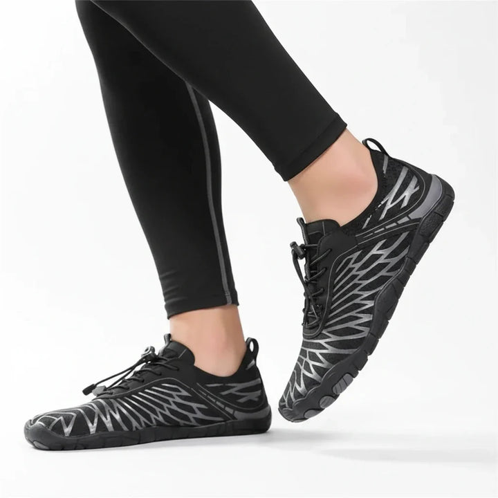 Model in black leggings walking in black barefoot-style shoes with silver line patterns, elastic bungee laces and flat, flexible soles. 21