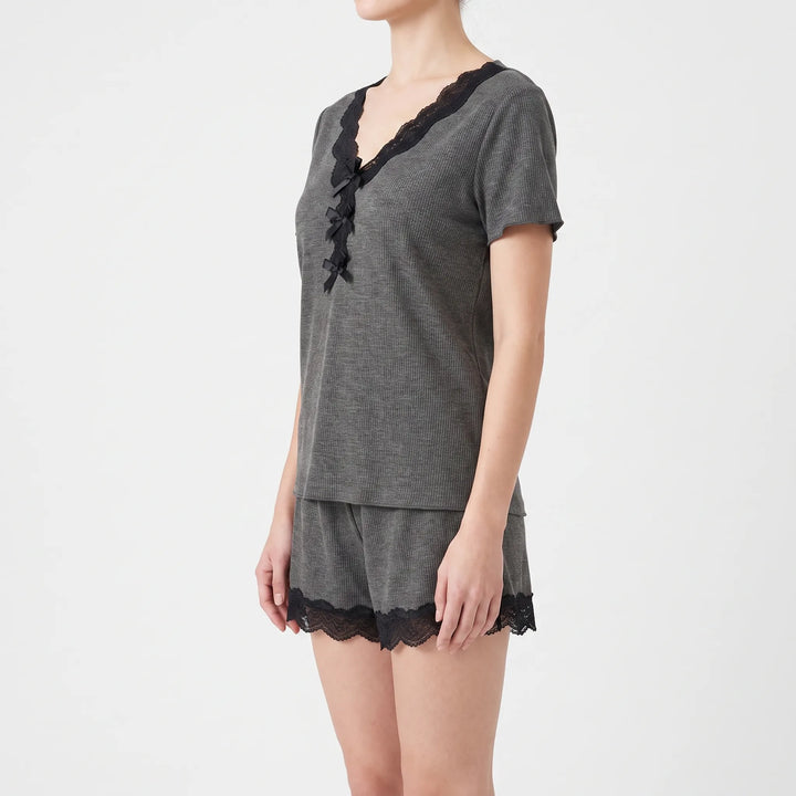 Three-quarter side view on a model, showing the lace-edged V-neck, row of black satin bows, short sleeves, and lace-hemmed gray shorts. 4