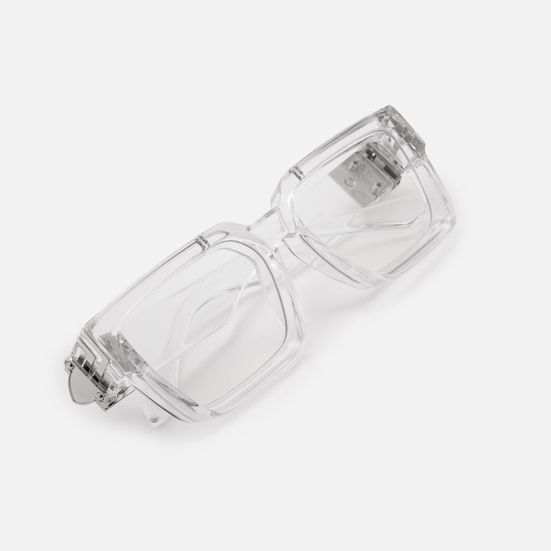 Folded clear rectangular glasses seen at an angle from above, showing the silver metal hinge detail on the thick transparent frame. 22