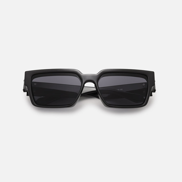 Black square sunglasses with dark lenses, folded and lying flat, seen from the front. 2