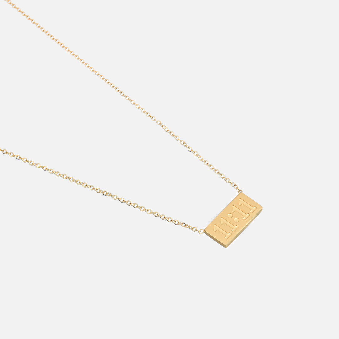 Lucky Elevens Necklace detail of the gold rectangular pendant with raised numerals on a fine chain.