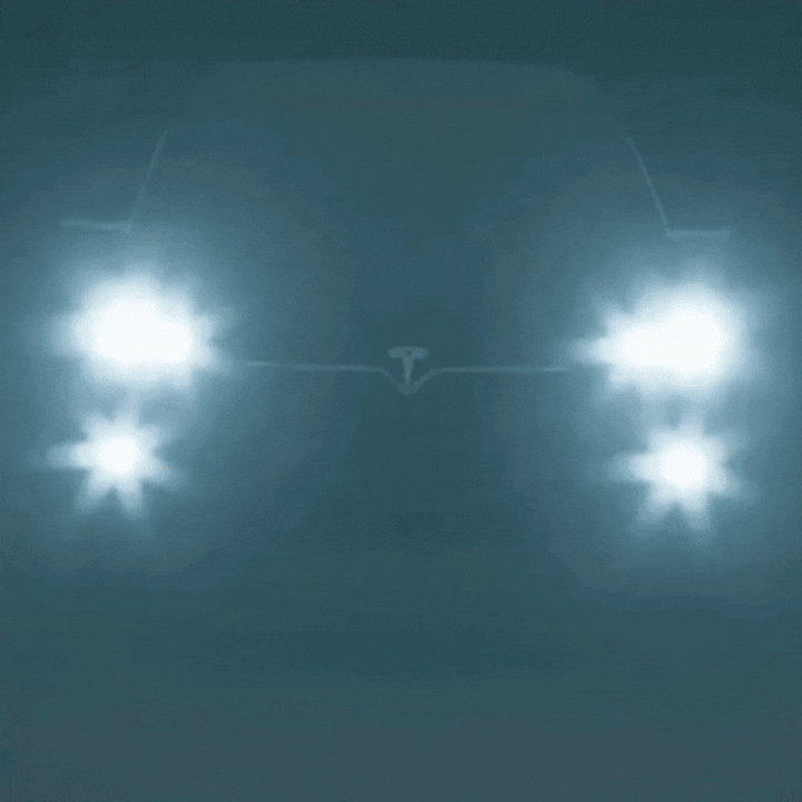 Detail of oncoming car headlights at night with harsh glare in a dark blue-teal haze.