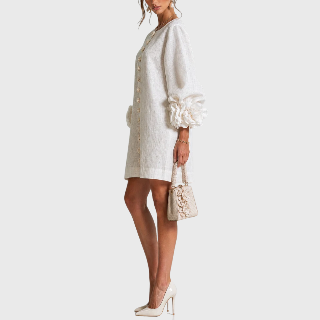 White linen mini dress with puff sleeves and flower buttons, side view.