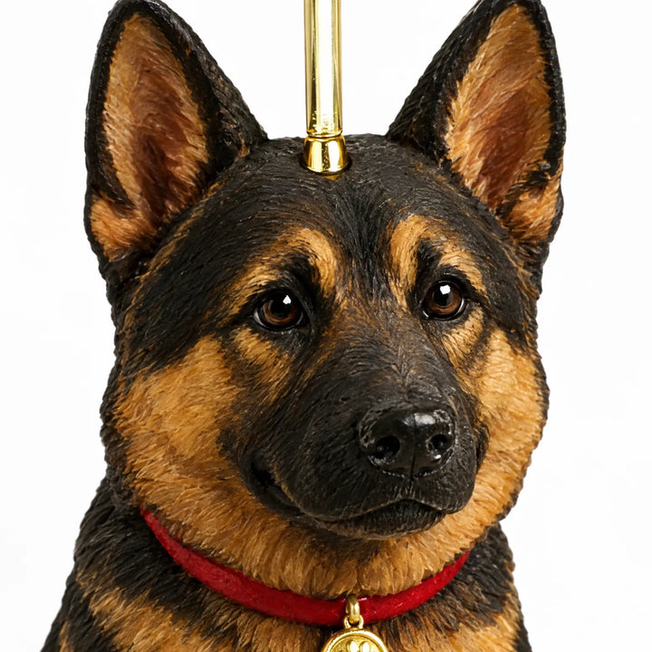 Close-up of one black and tan dog ornament's head, showing textured fur, brown eyes, a red collar, gold tag and gold hanging loop. 3