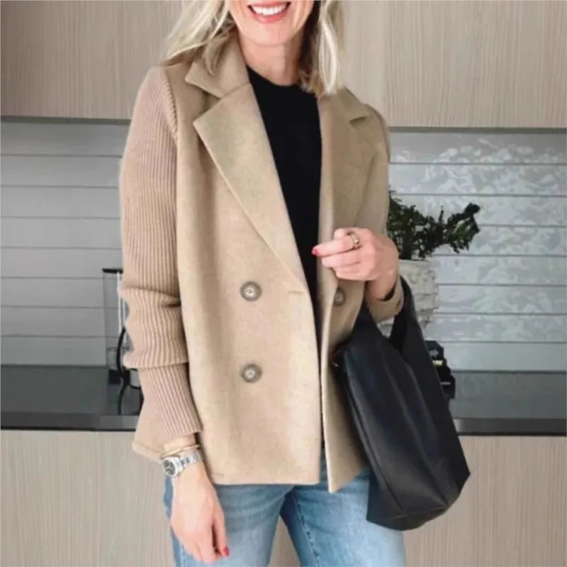 Smiling woman wears the beige double-breasted jacket with ribbed sleeves, holding a black tote bag in a kitchen 2