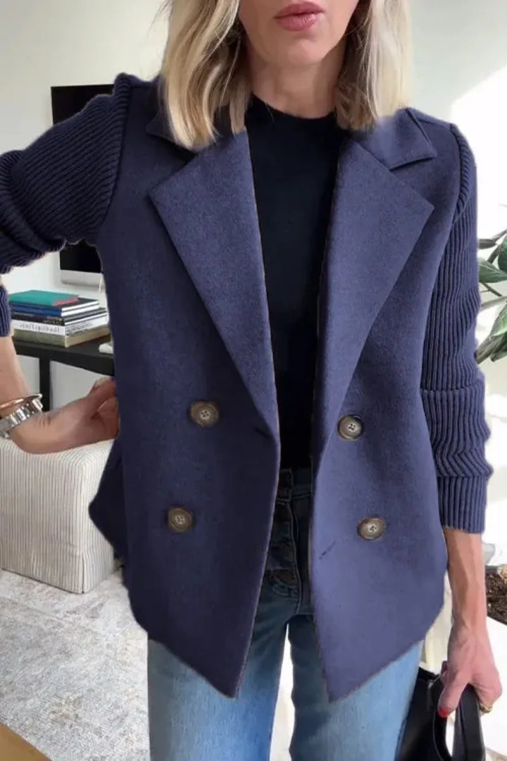 Close-up of the navy jacket worn open over a black top, showing four buttons and ribbed sleeves 9