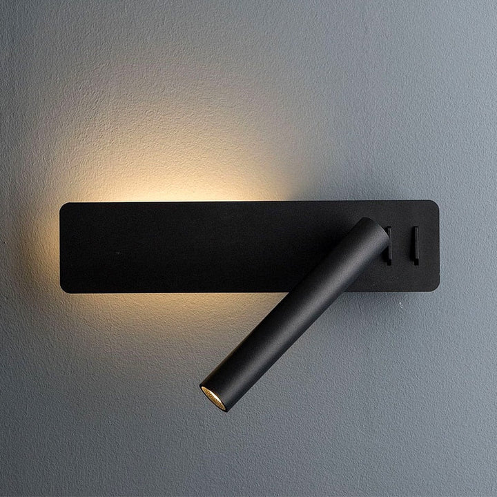Black wall light with the swivel spot tube pointing down and a soft warm halo behind the plate.