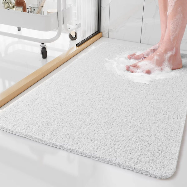 White version of the looped mat on a bathroom floor, with soapy bare feet standing on it and a storage cart behind. 5