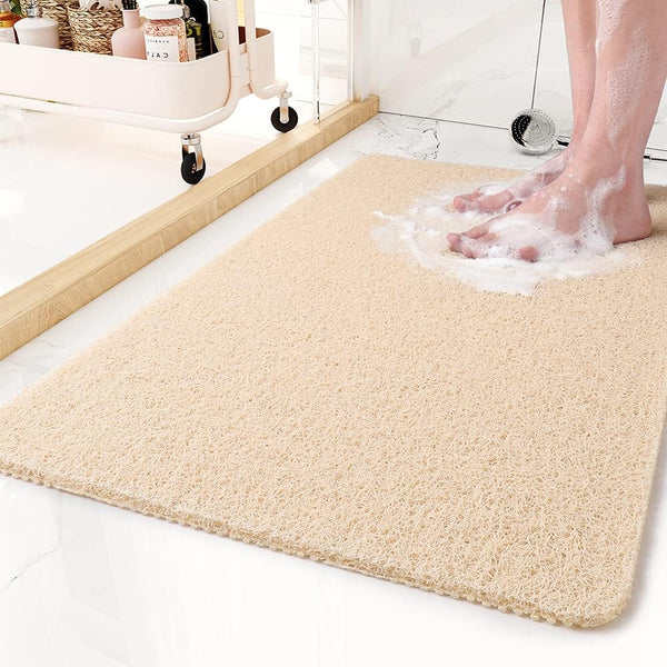 Beige version of the looped mat on a bathroom floor, with soapy bare feet standing on it and a storage cart nearby. 6